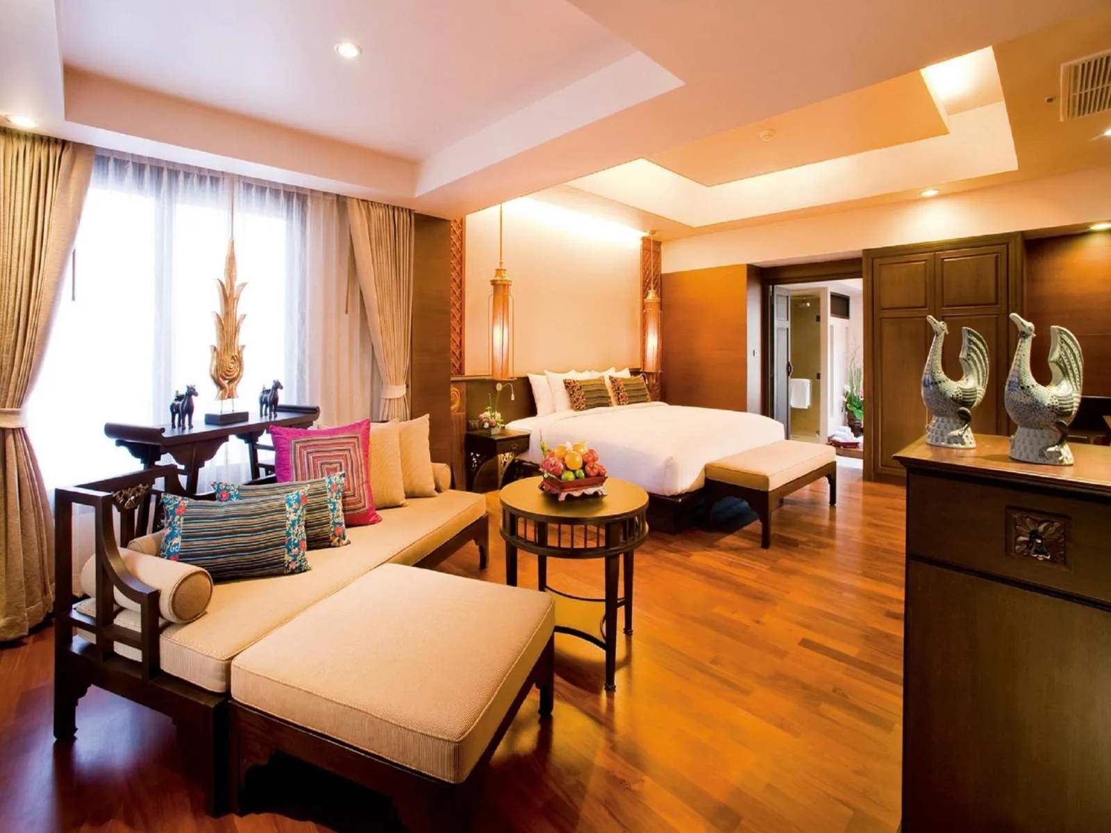 Zona de estar de la suite en Siripanna Villa Resort & Spa Chiang Mai -SHA Extra Plus con sofá y una cama king.