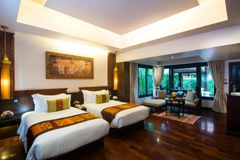 Suite con dos camas en Siripanna Villa Resort & Spa Chiang Mai -SHA Extra Plus con grandes ventanales y zona de estar.