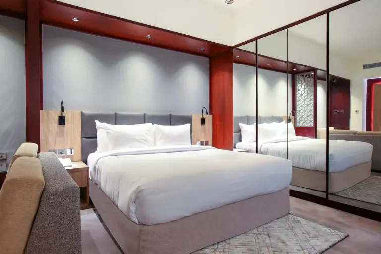 Chambre lumineuse à Sitara Hotel Apartment à Dubaï avec grand lit et panneaux muraux miroir