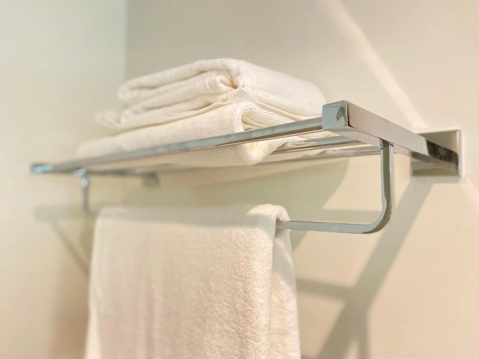 Serviettes propres pliées sur un porte-serviettes dans une salle de bains de Sitara Hotel Apartment à Dubaï