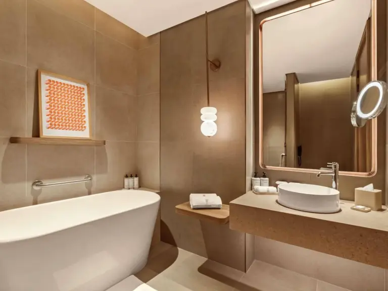 SO Ras Al Khaimah Hotel & Resort-Ultra All Inclusive – hôtel à Ras Al Khaimah, Émirats arabes unis – une salle de bains avec une baignoire, un lavabo et un miroir au SO Ras Al Khaimah Hotel & Resort-Ultra All Inclusive à Ras al Khaimah