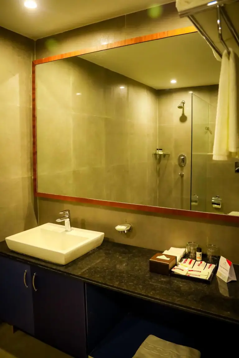 Badezimmer im Soaltee Westend Itahari in Dharan mit Waschtisch, großem Spiegel und Duschbereich