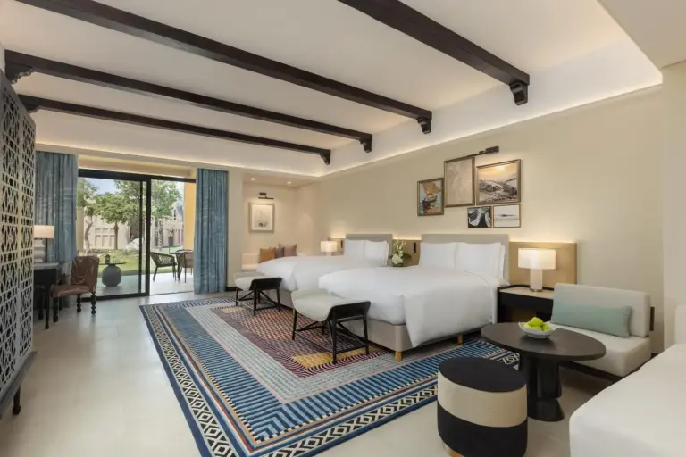 Sofitel Ras Al Khaimah Al Hamra Beach Resort – hôtel à Ras Al Khaimah, Émirats arabes unis – une chambre avec deux lits et un salon au Sofitel Ras Al Khaimah Al Hamra Beach Resort à Ras Al Khaimah