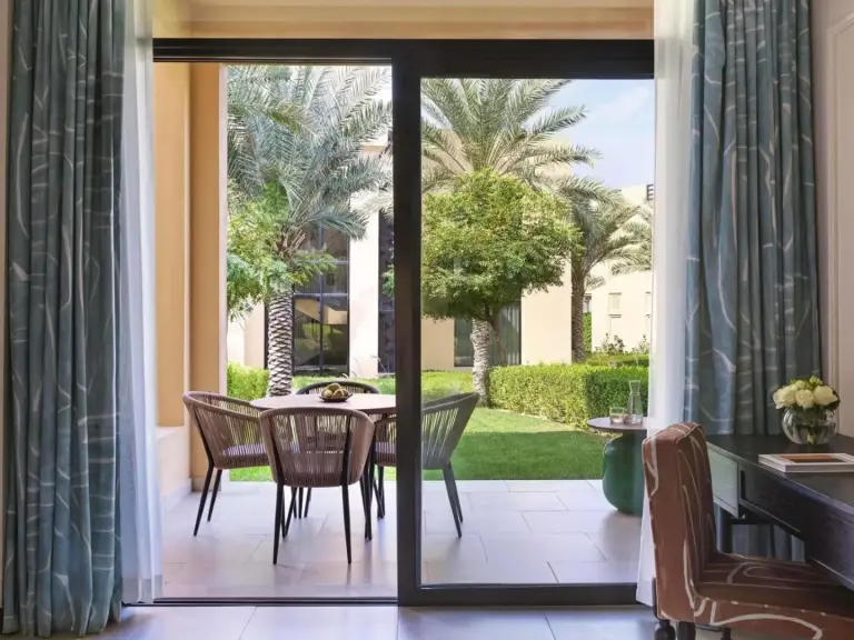 Sofitel Ras Al Khaimah Al Hamra Beach Resort – hôtel à Ras Al Khaimah, Émirats arabes unis – une porte vitrée donnant sur un patio avec table et chaises au Sofitel Ras Al Khaimah Al Hamra Beach Resort à Ras Al Khaimah