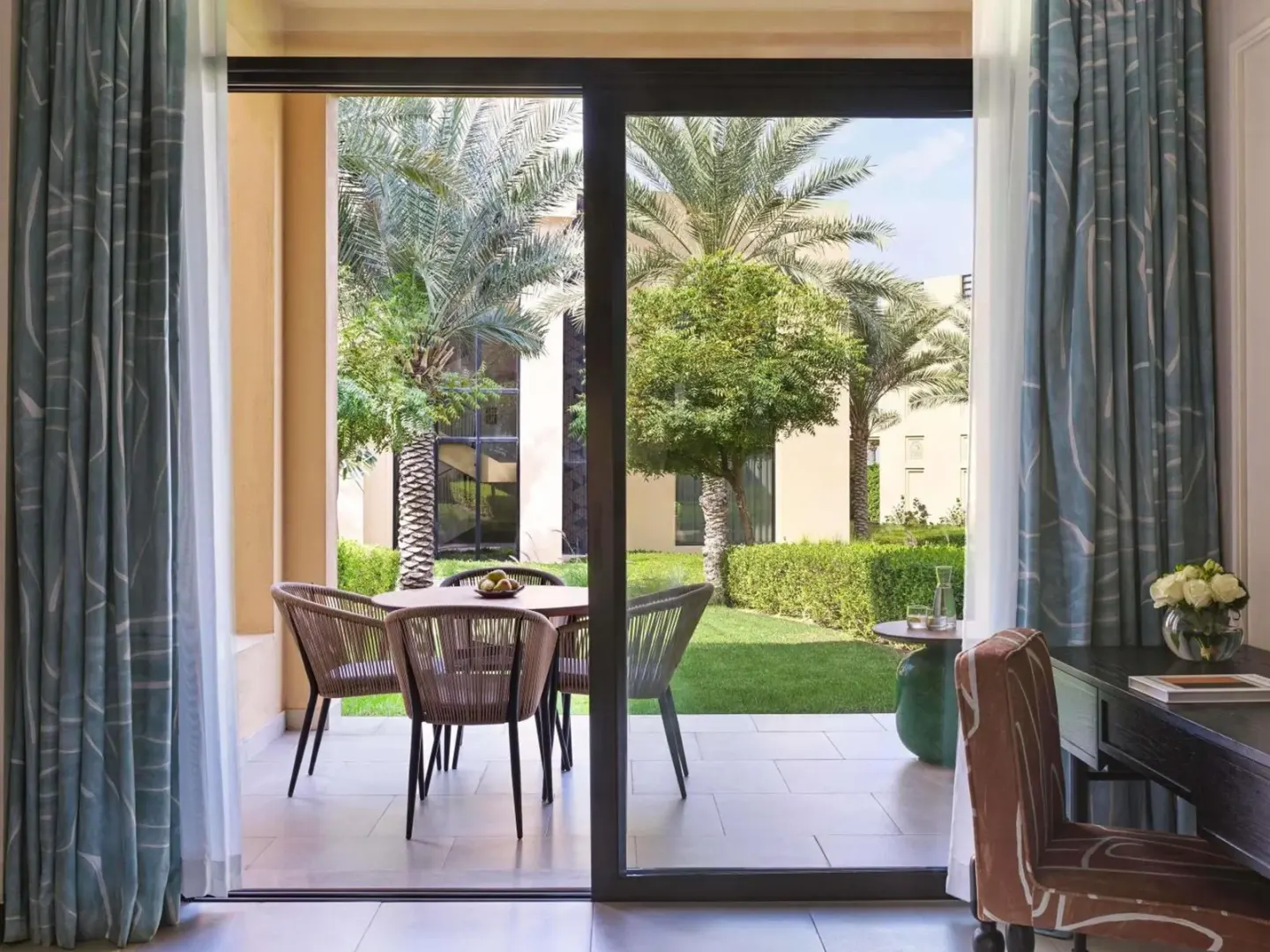 Sofitel Ras Al Khaimah Al Hamra Beach Resort – hôtel à Ras Al Khaimah, Émirats arabes unis – une porte vitrée donnant sur un patio avec table et chaises au Sofitel Ras Al Khaimah Al Hamra Beach Resort à Ras Al Khaimah