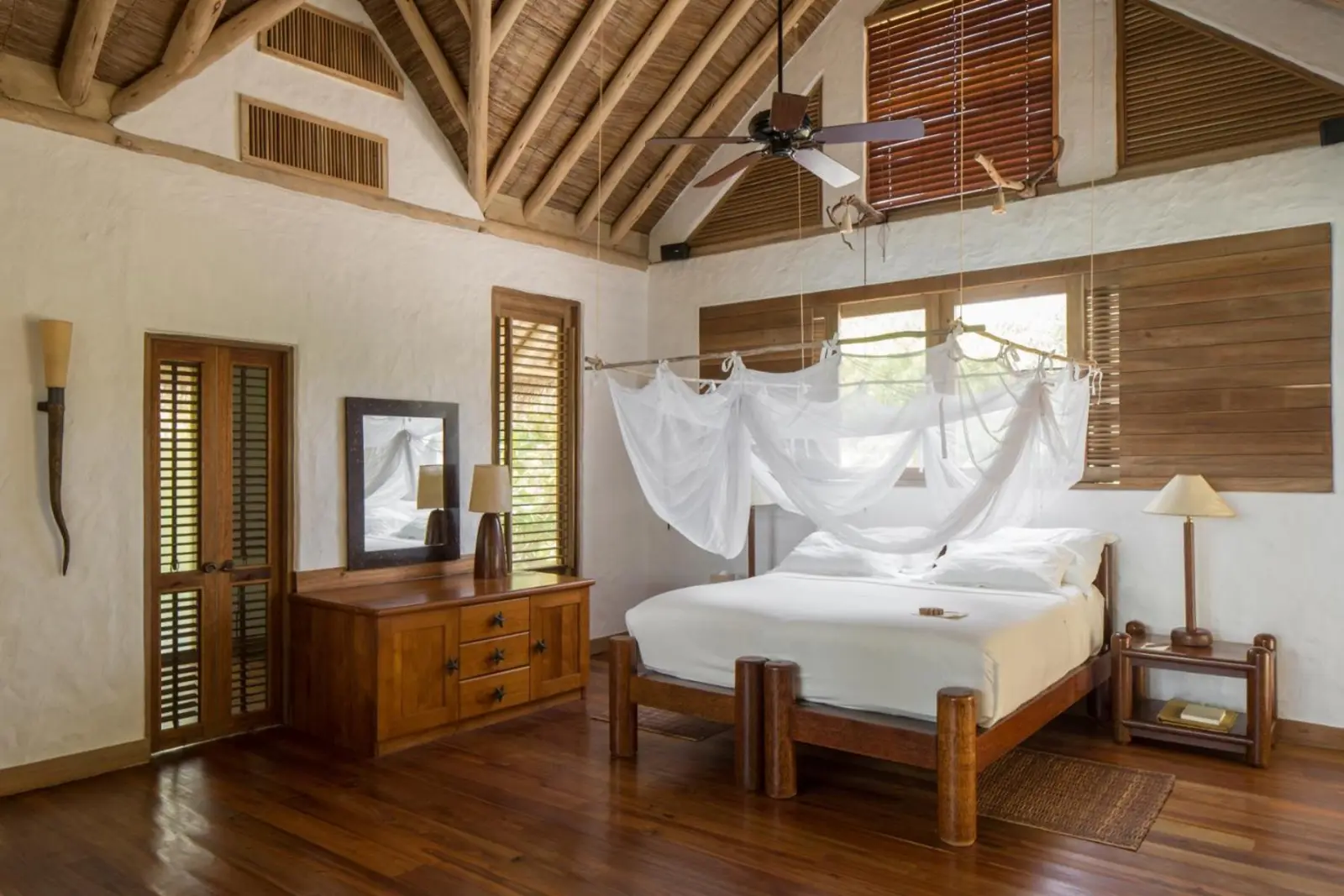 Cozy bedroom interior in a Soneva Fushi villa with wooden furnishings.