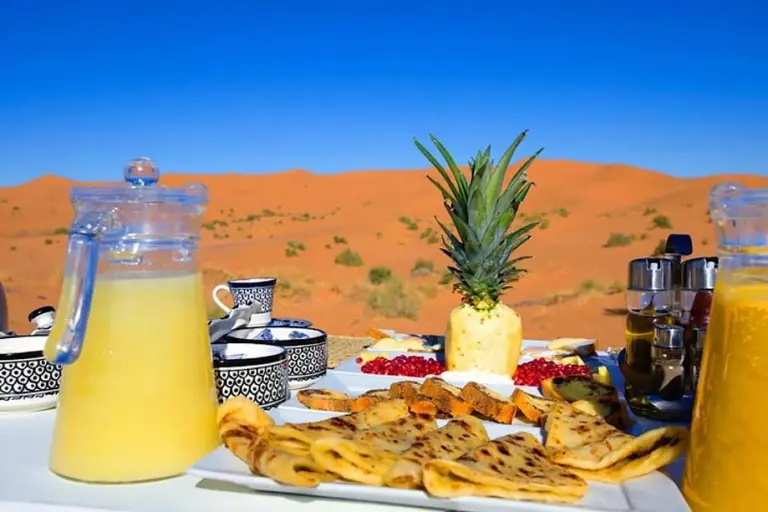 Breakfast spread at Soul Dunes Luxury Camp in Merzouga with pastries, juice, and desert dune views