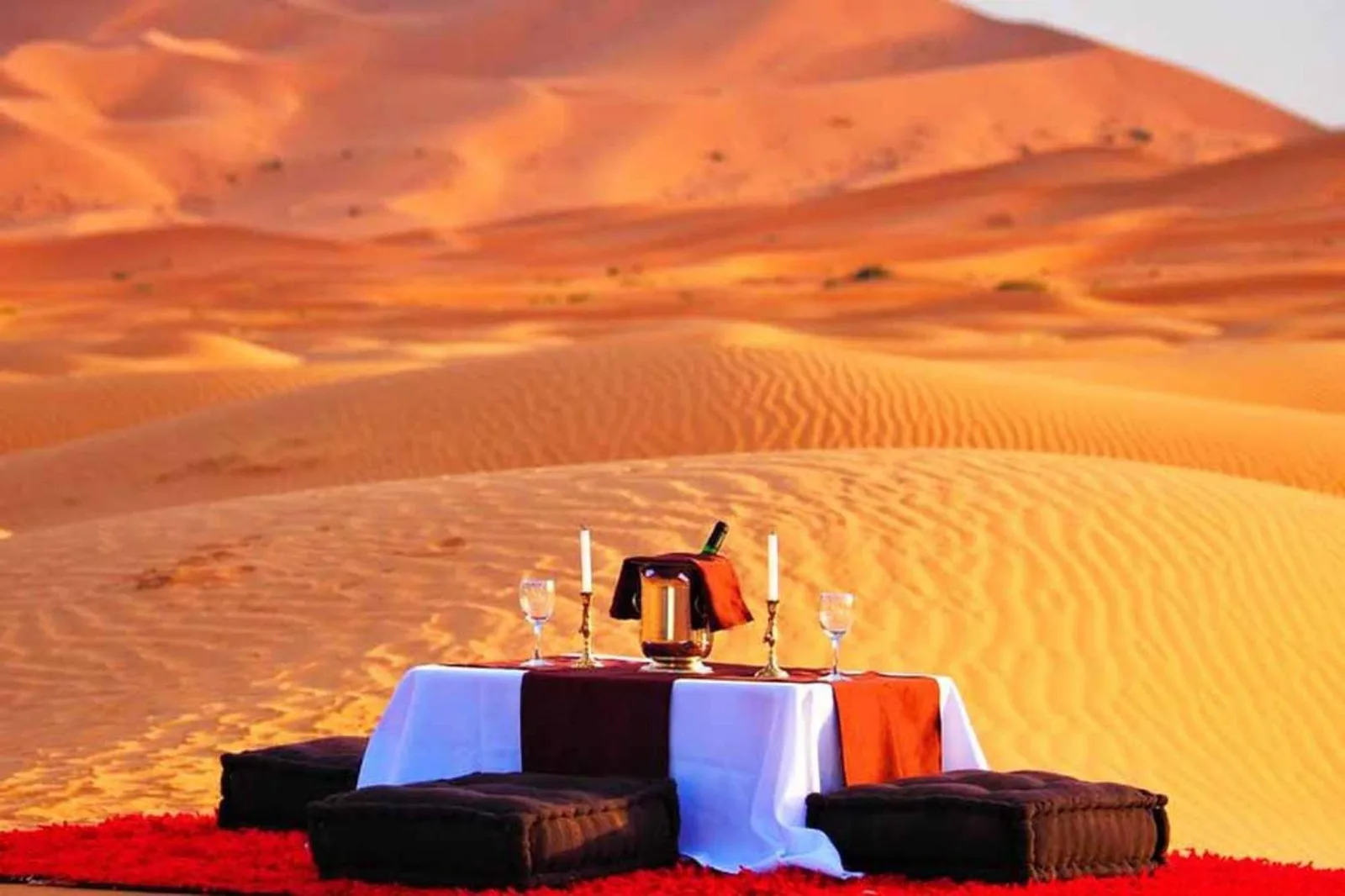 Outdoor dining setup at Soul Dunes Luxury Camp in Merzouga with table, cushions, and panoramic sand dune views