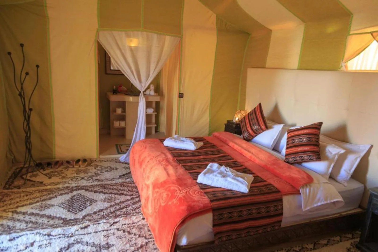 Double bed tent room at Soul Dunes Luxury Camp in Merzouga with decorative pillows and private wash area entrance