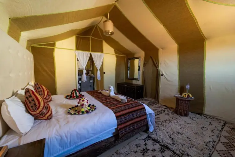 Luxury suite tent interior at Soul Dunes Luxury Camp in Merzouga with a large bed, seating area, and patterned carpets