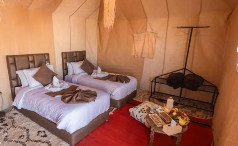 Twin tent suite at Soul Dunes Luxury Camp in Merzouga with separate beds, red rug, and seating bench