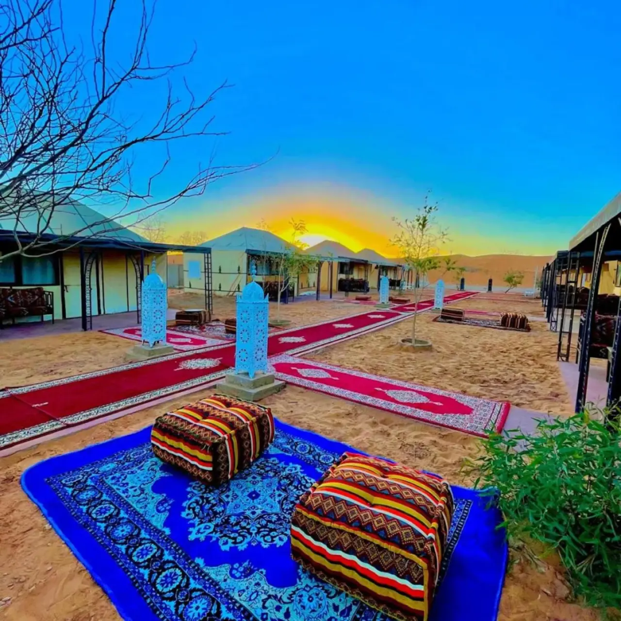 Außenansicht von Starlight Erg Luxury Camp in Merzouga mit Wüstenwegen und Zelten bei Sonnenuntergang