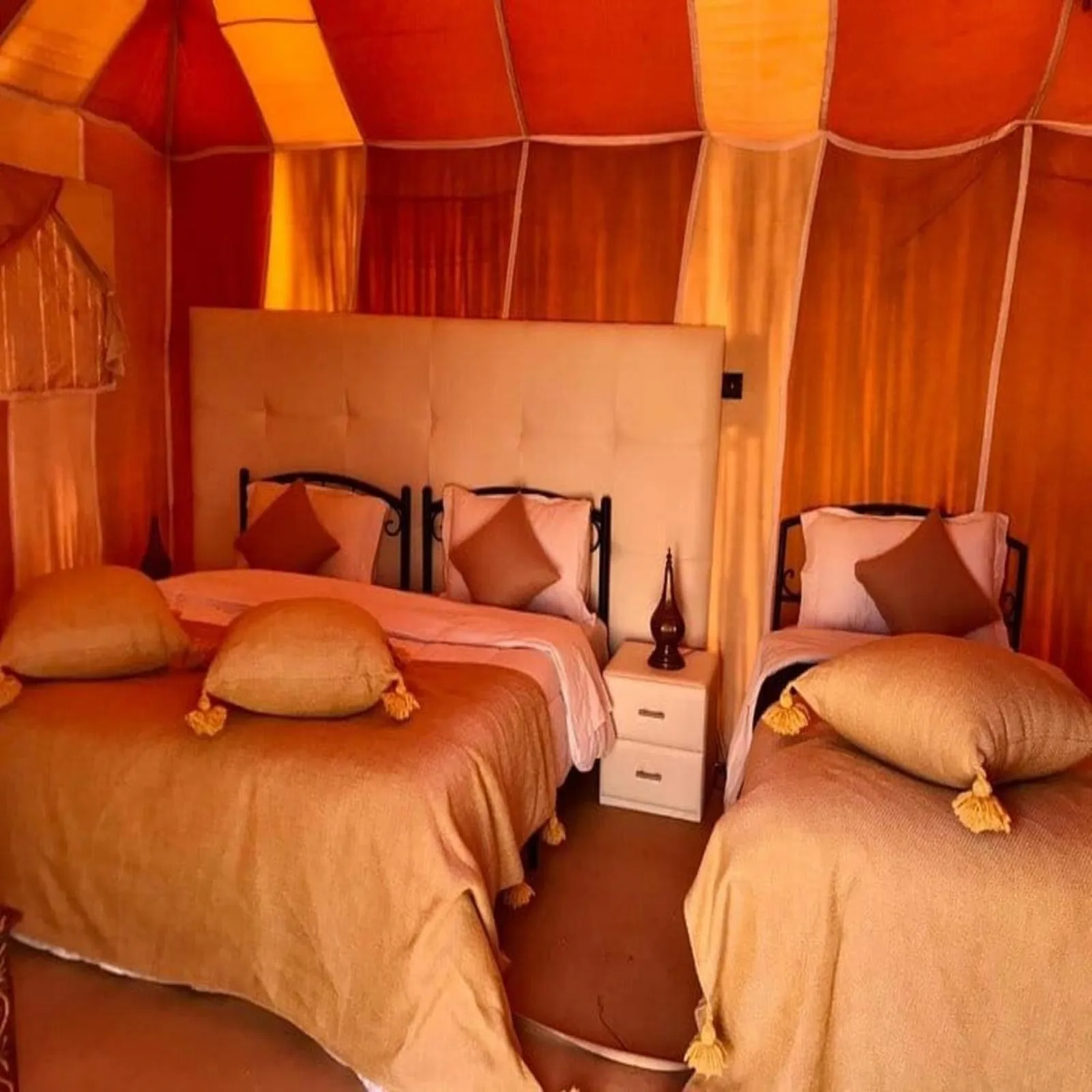 Innenraum eines Zwillingszelts im Starlight Erg Luxury Camp in Merzouga mit zwei Betten und warmer Einrichtung