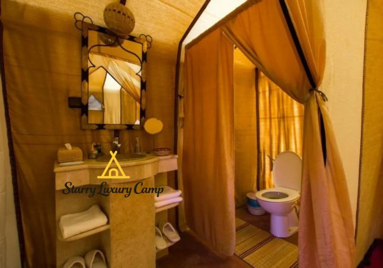 Baño privado en STARRY LUXURY CAMP en Merzouga con lavabo, espejo y zona de inodoro.