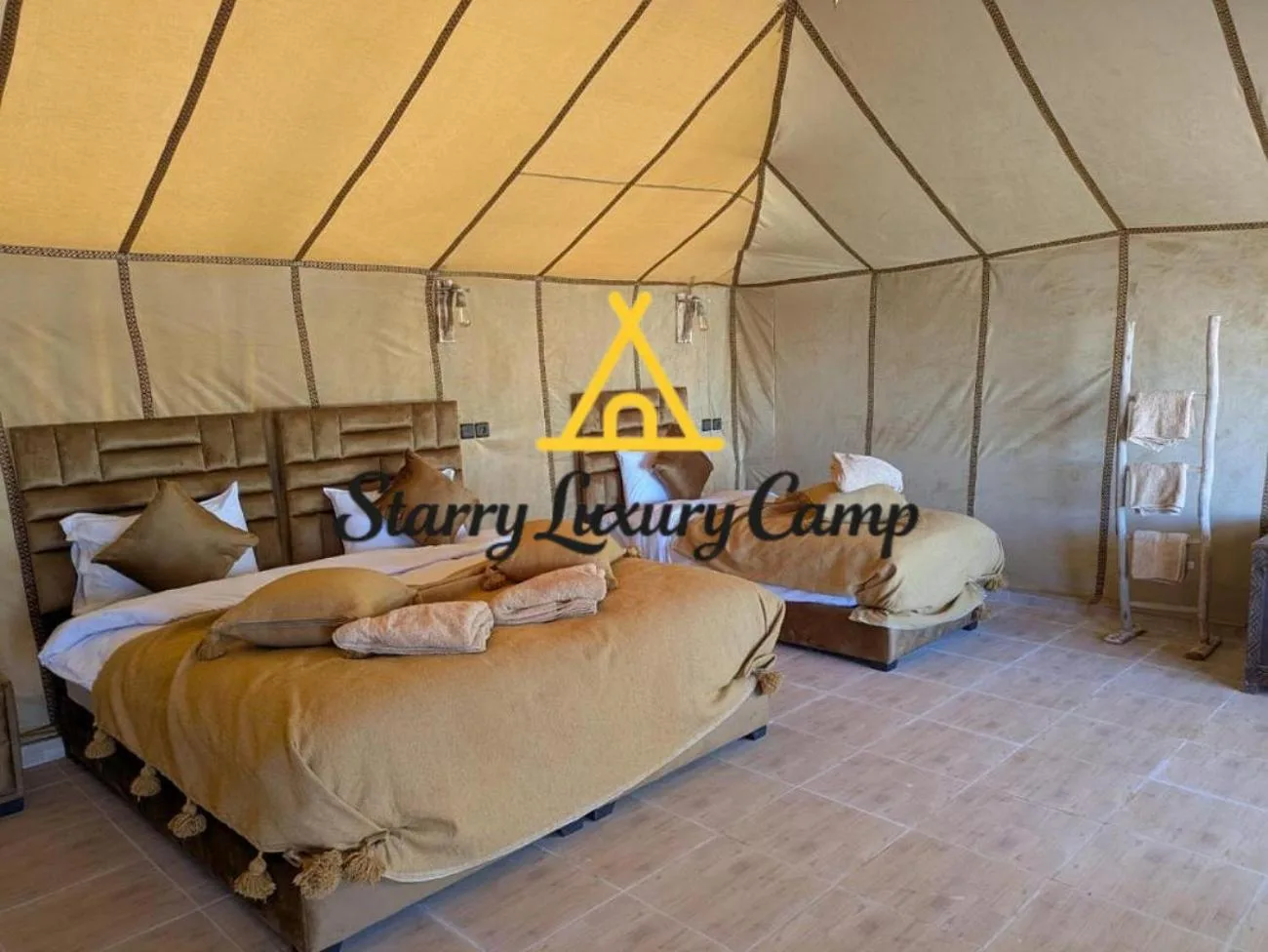 Habitación con cama doble en STARRY LUXURY CAMP en Merzouga con dos camas e interiores neutros de tienda.