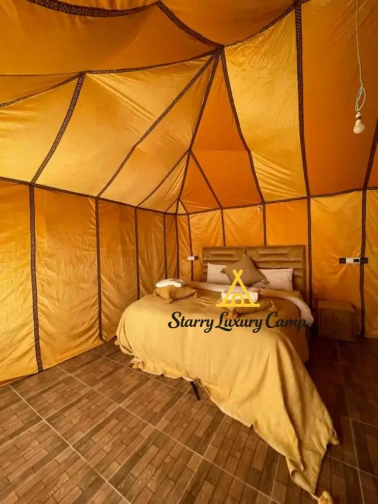 Dormitorio estándar de tienda en STARRY LUXURY CAMP en Merzouga con una cama doble y cálidas paredes de lona dorada.
