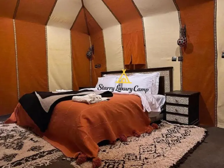 Acogedora habitación de tienda en STARRY LUXURY CAMP en Merzouga con una cama doble y una decoración cálida de estilo desértico.