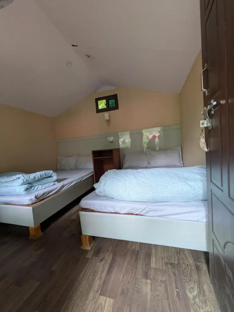 Sukute River Fun Beach Resort – hotel en Nagarkot, Nepal – dos camas en una habitación pequeña con una ventana en Sukute River Fun Beach Resort en Dolālghāt