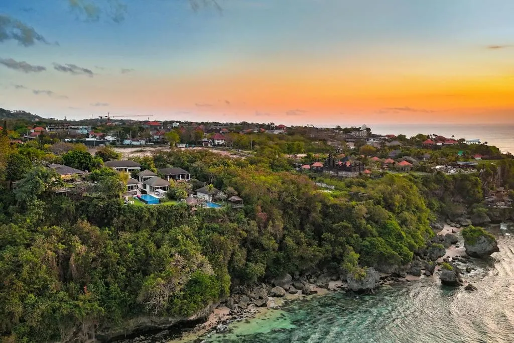 Aerial view of Suluban Cliff Bali Villa in Uluwatu, showcasing the landscape and sunset