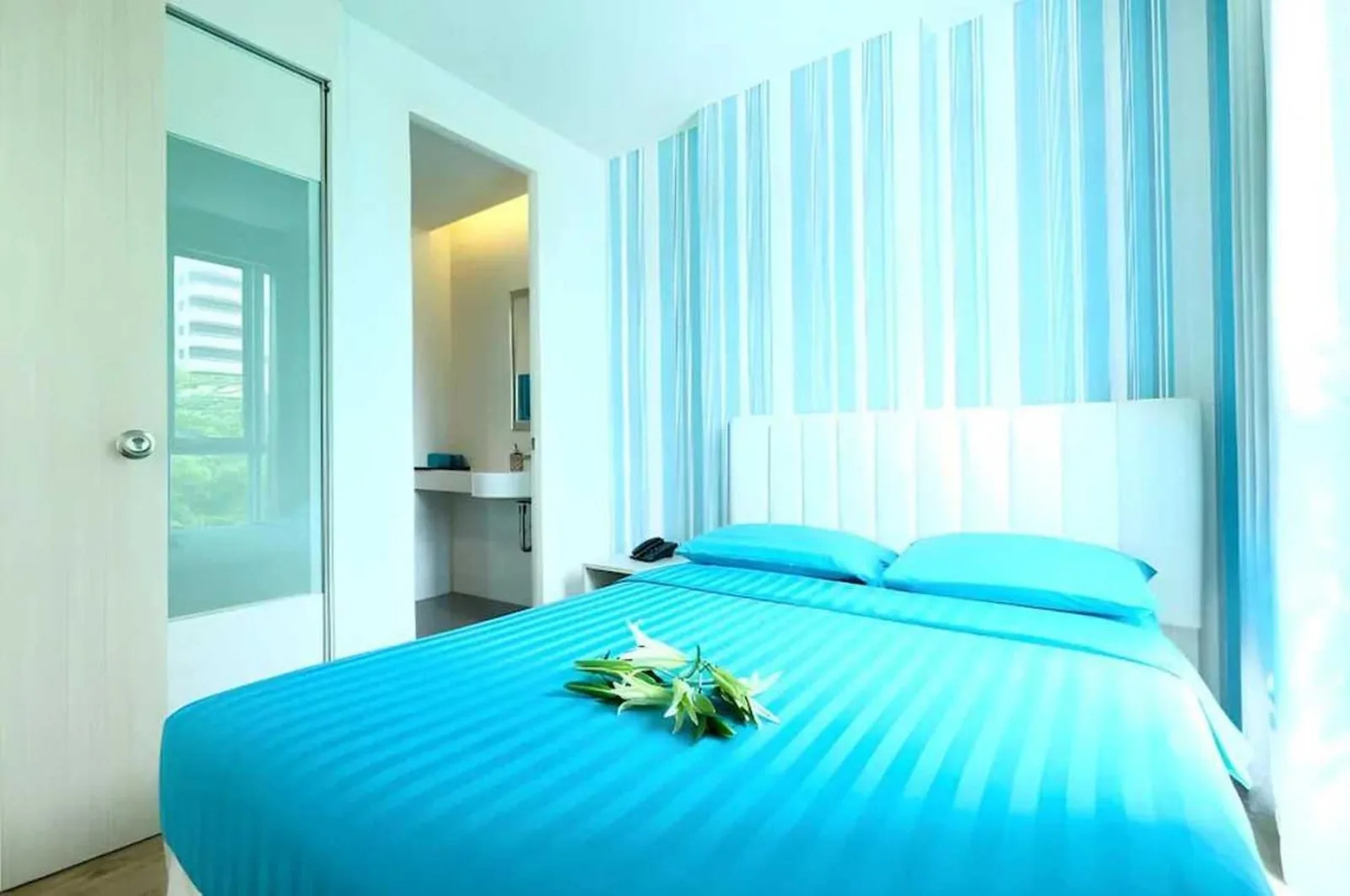 Dormitorio compacto y luminoso en Sunday Beachfront View Jomtien Pattaya con ropa de cama azul y acceso al baño privado
