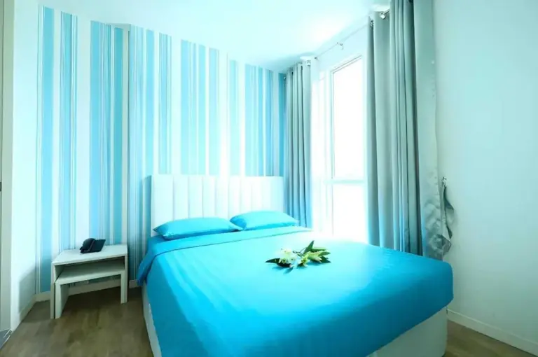 Dormitorio estándar luminoso en Sunday Beachfront View Jomtien Pattaya con ropa de cama azul y paredes a rayas
