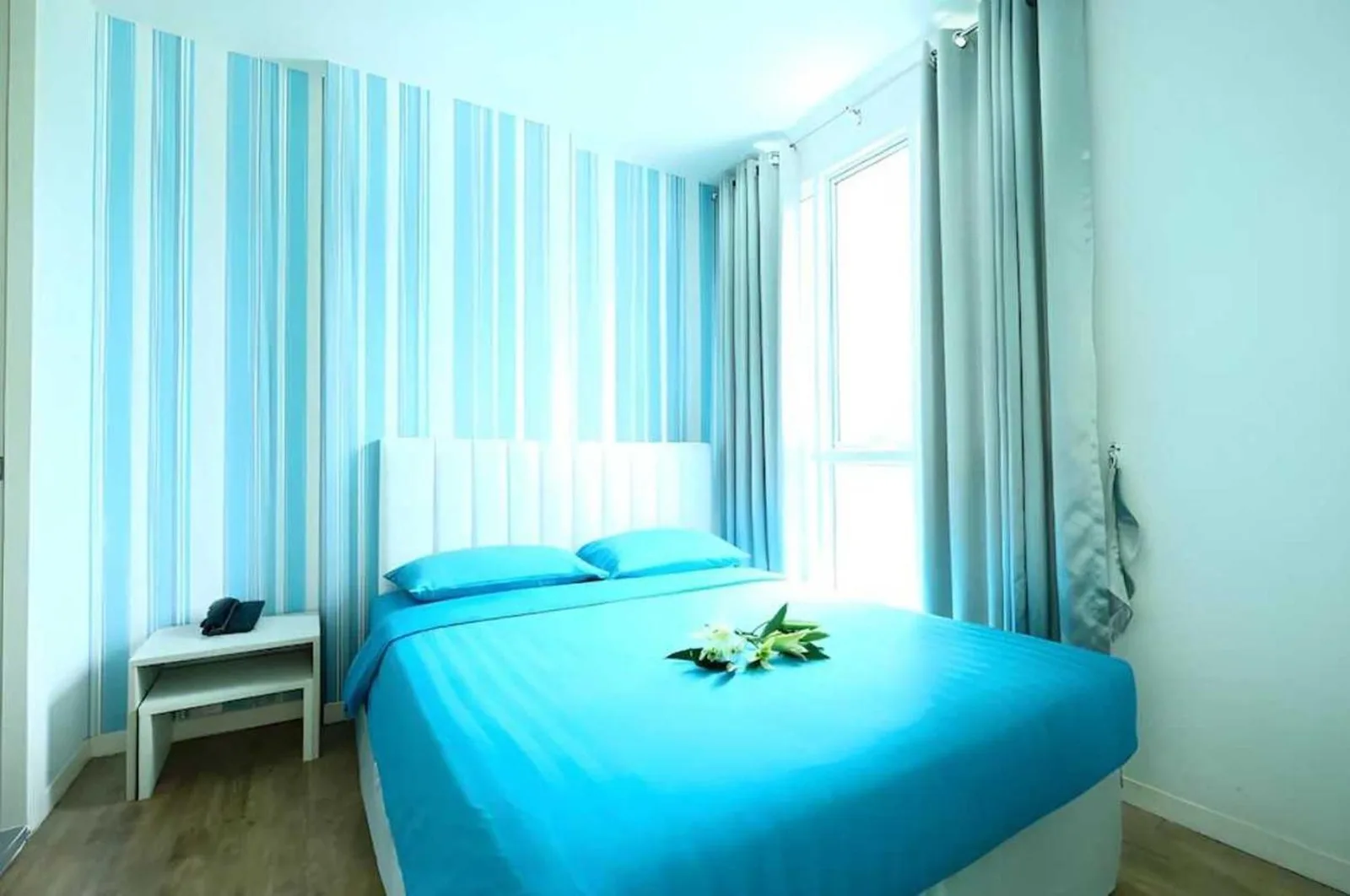 Dormitorio estándar luminoso en Sunday Beachfront View Jomtien Pattaya con ropa de cama azul y paredes a rayas