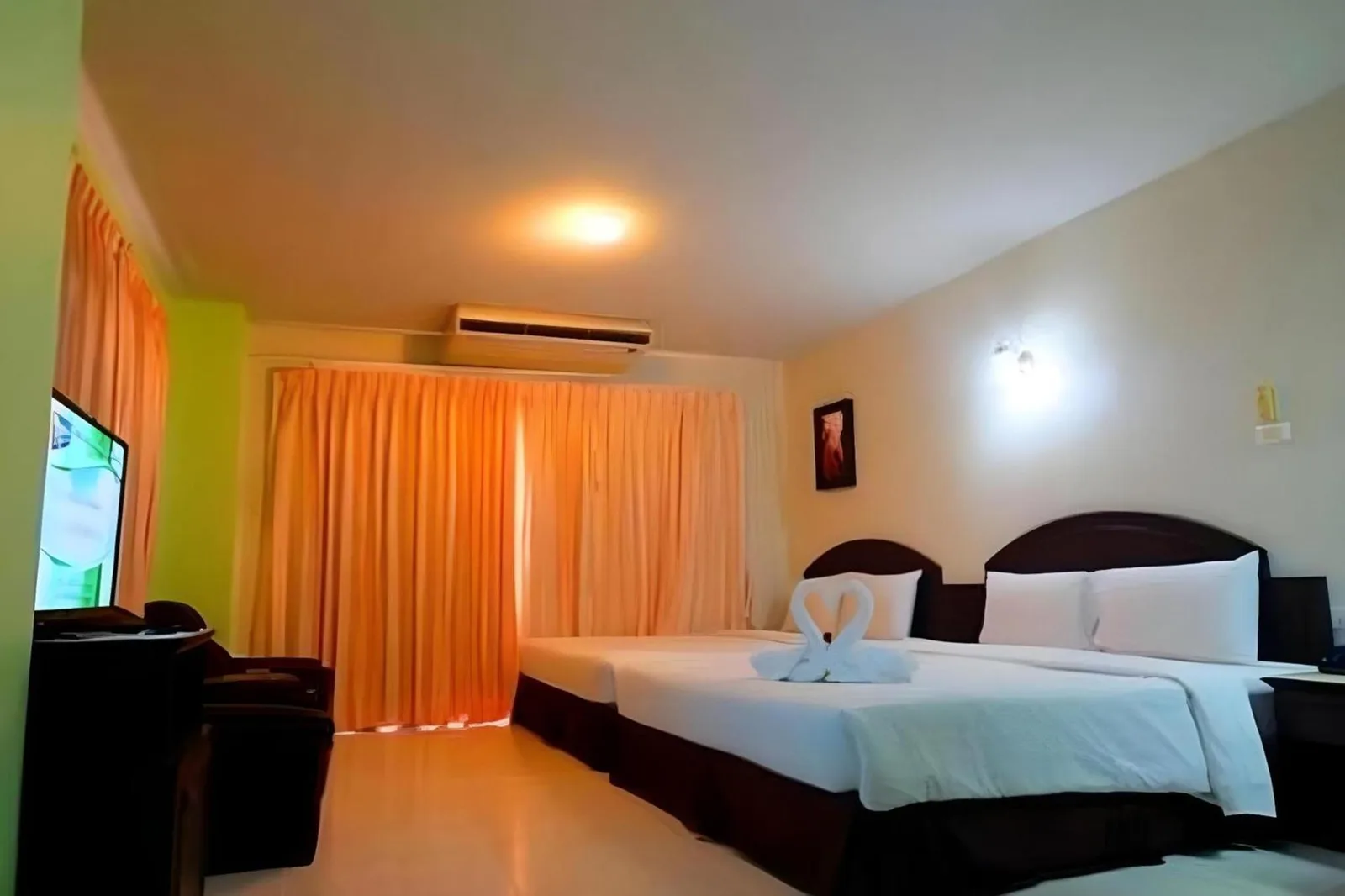 Habitación doble compacta en Sunday JA Plus Hotel en Pattaya con iluminación cálida y cortinas