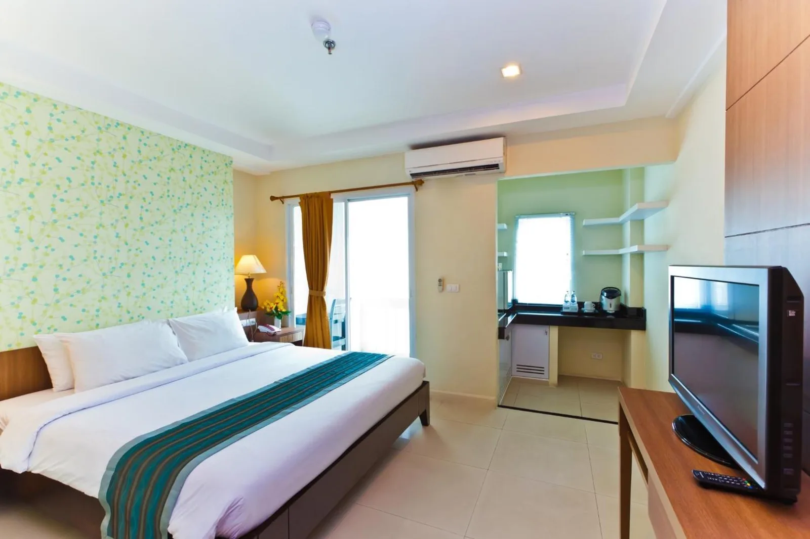 Habitación de huéspedes en Sunday Platinum Suites Bangkok con cabecero estampado y lámpara de mesilla