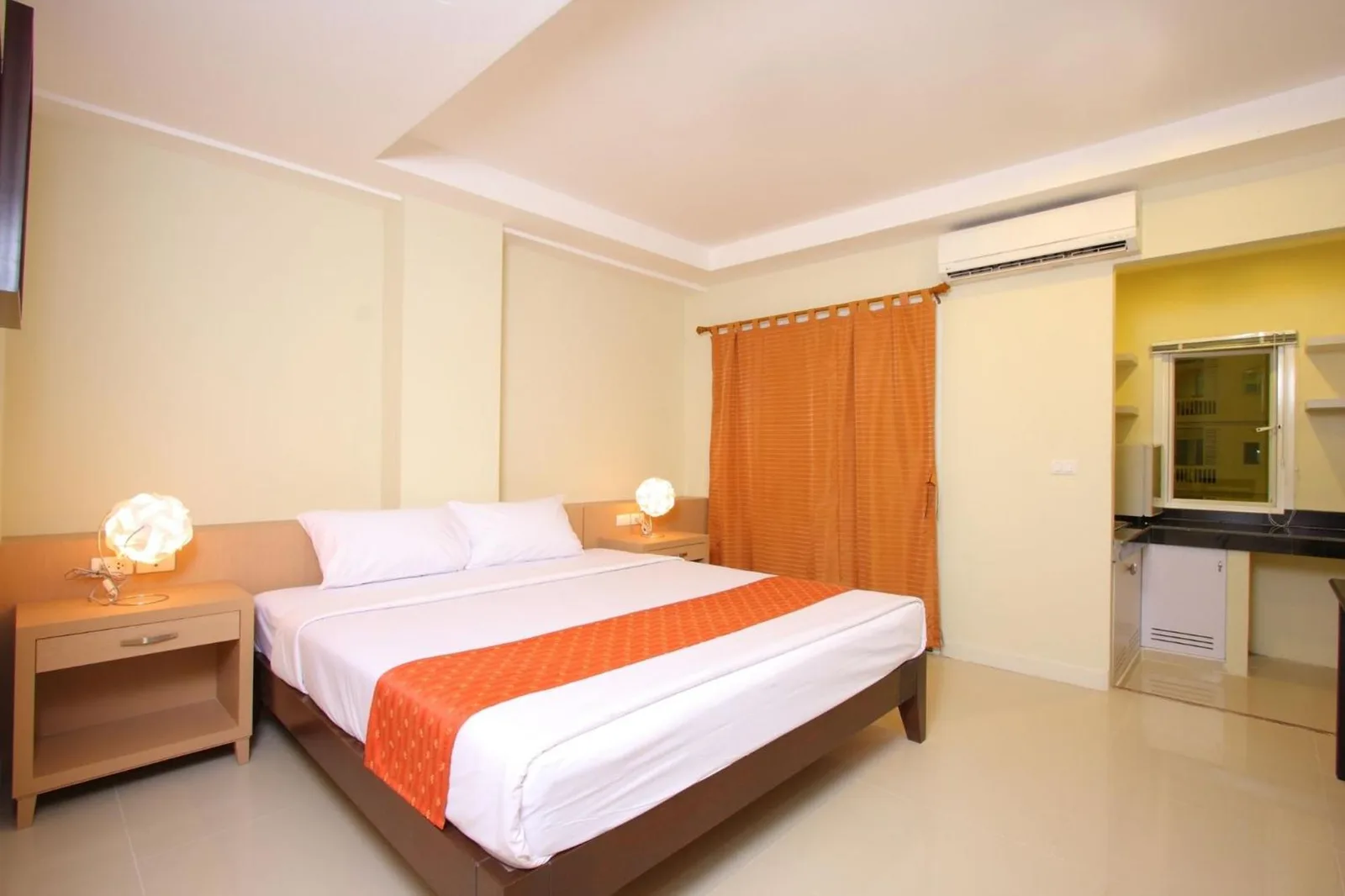 Habitación luminosa en Sunday Platinum Suites Bangkok con una cama doble y detalles en naranja