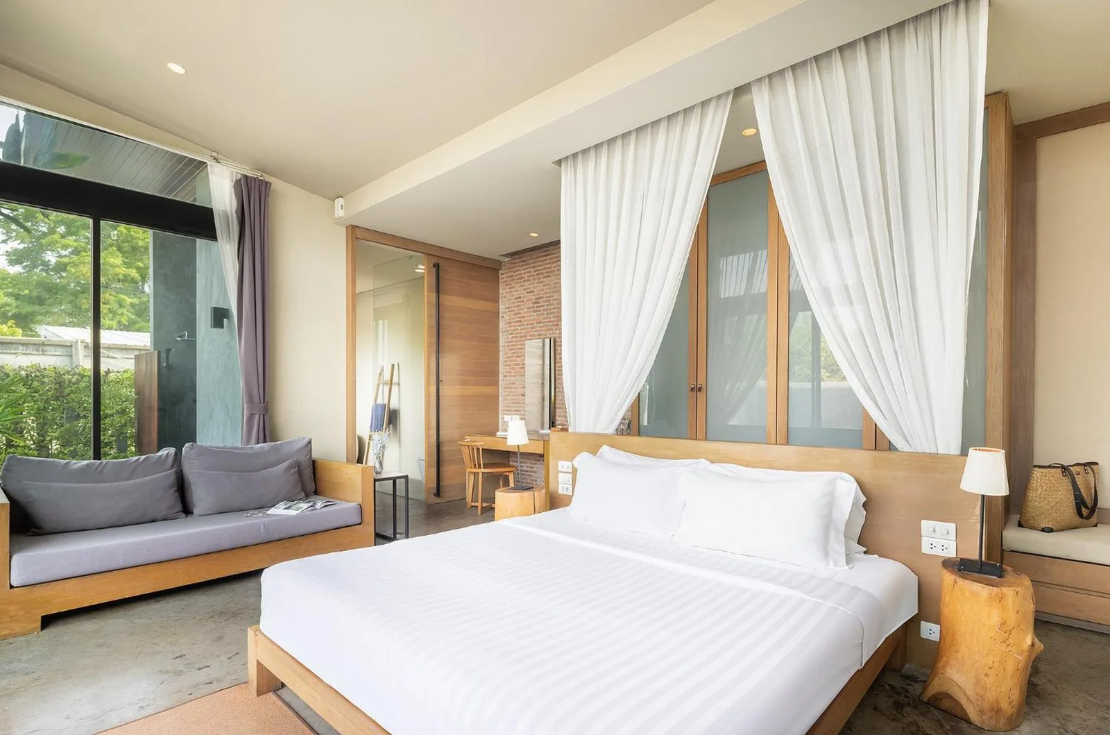 Bedroom lounge area at Sunday Sea Two Pool Villa Pattaya with a sofa, bed, and garden views