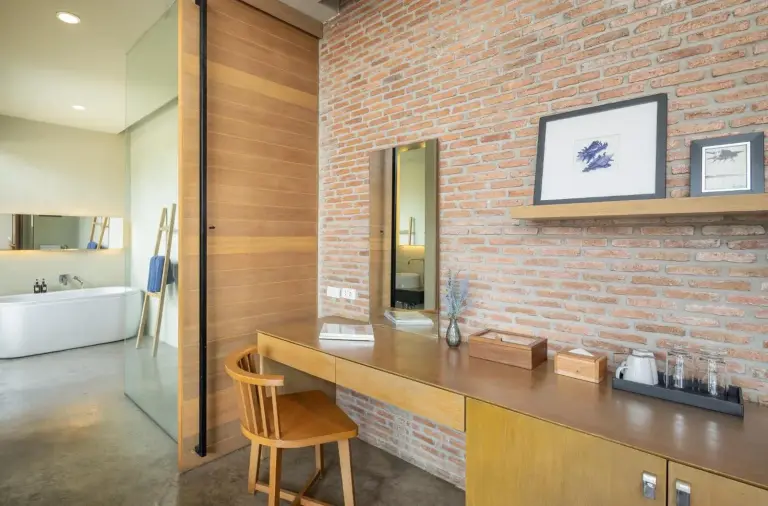 Vanity desk area at Sunday Sea Two Pool Villa Pattaya beside a brick accent wall and bathroom entrance