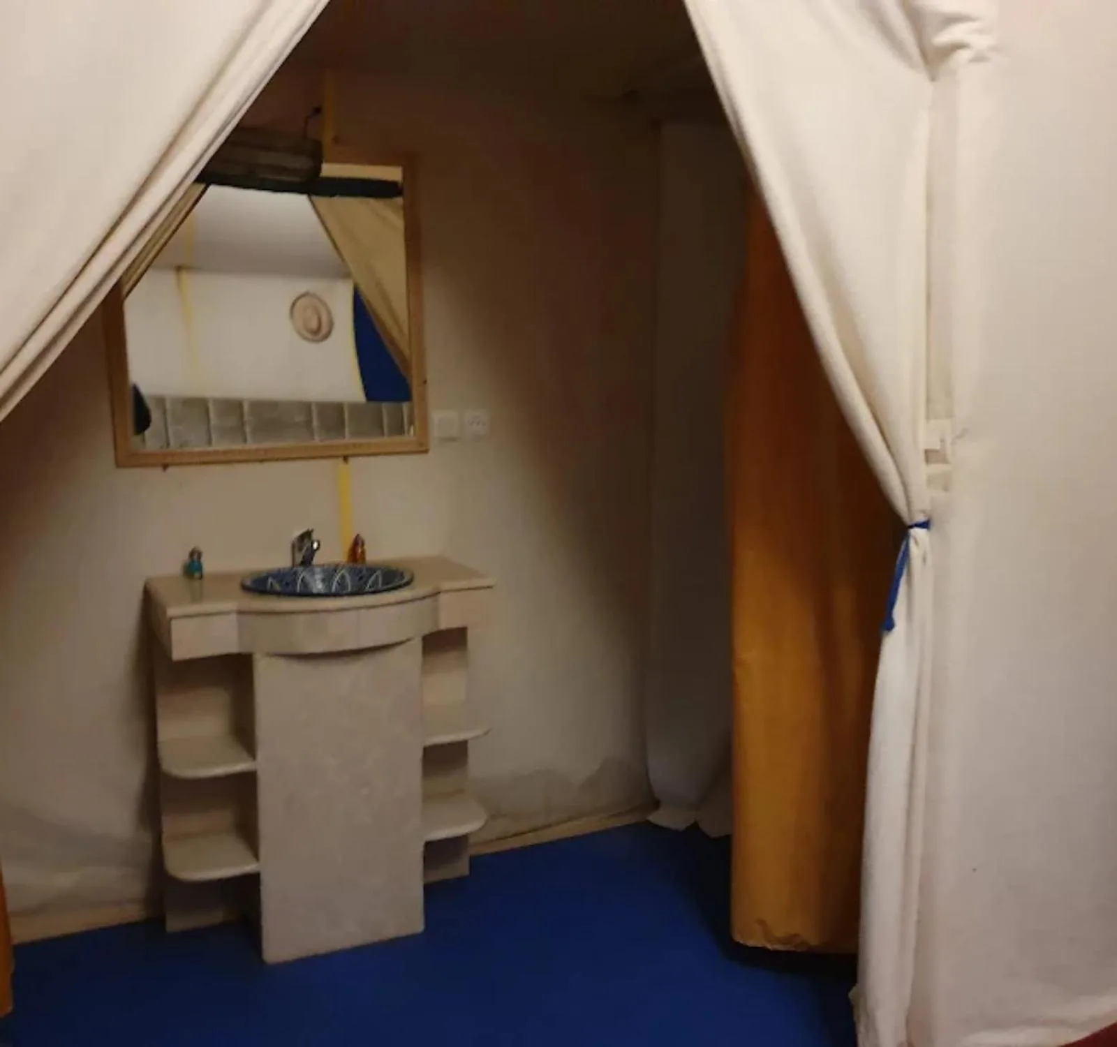 Espace lavabo de salle de bains au Sunshine luxury desert camp à Merzouga avec un miroir, un lavabo carrelé et l’entrée privée de la salle de bains de la tente.