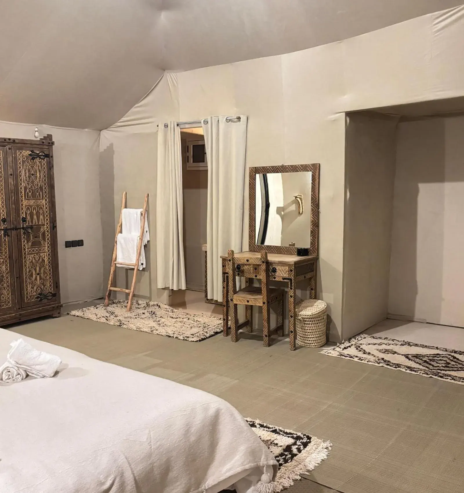Coiffeuse et espace dressing au Sunshine luxury desert camp à Merzouga avec un miroir, un bureau en bois et un espace penderie dans la tente.