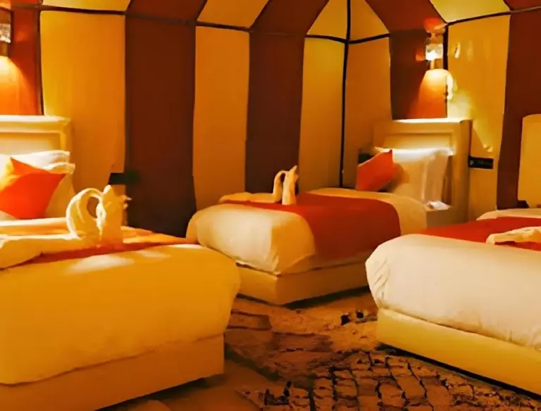Sunshine luxury tent in Merzouga quad room with four beds, neutral decor, and a large tented interior.