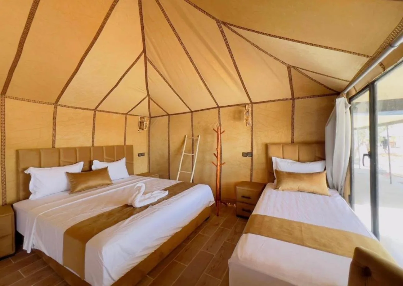 Sunshine luxury tent in Merzouga twin tent room with two beds, modern furnishings, and a bright canvas interior.