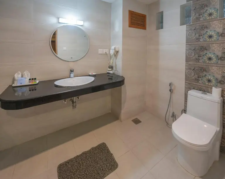 Modern bathroom at Sunshine Resort Pokhara in Pokhara with sink, mirror, toilet, and tiled shower area.