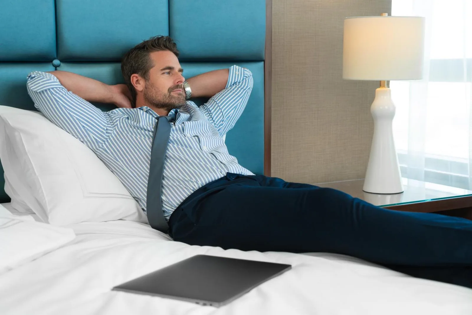Geschäftsreisender entspannt auf einem Bett in einem Gästezimmer des Swissôtel Al Ghurair Dubai