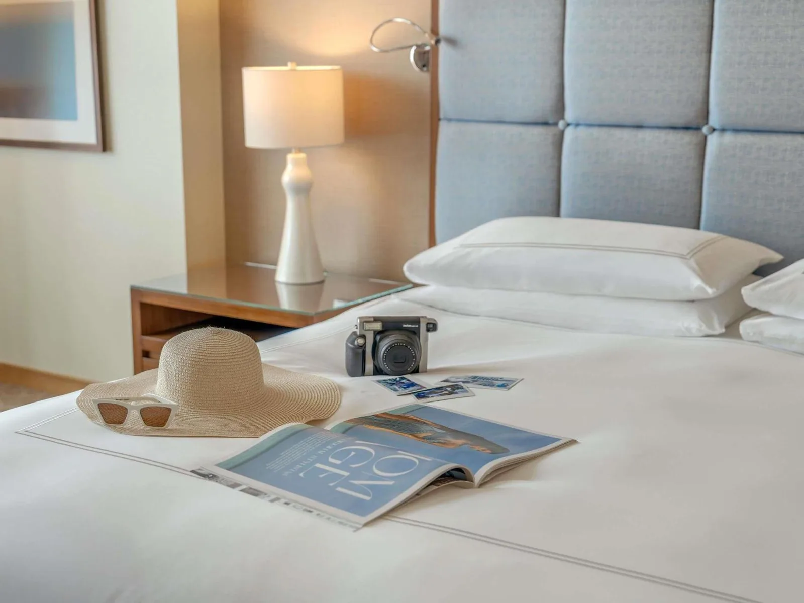 Zimmerdetails im Swissôtel Al Ghurair Dubai mit Hut, Kamera, Magazin und Bett