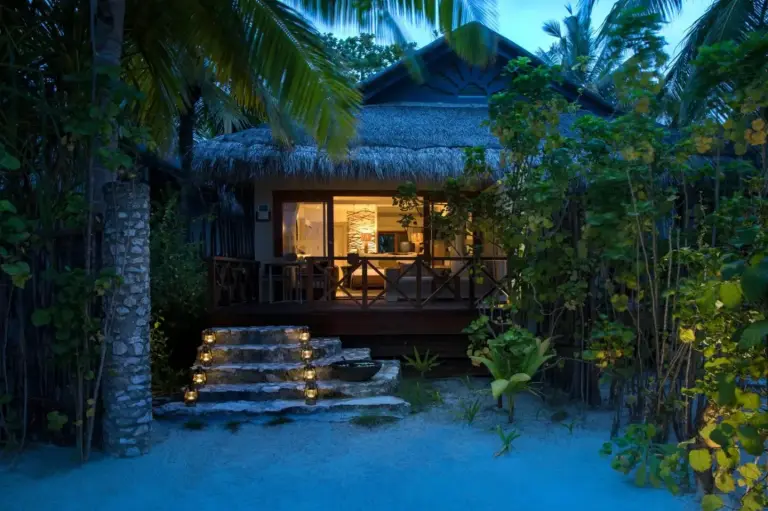 Entrada nocturna a un bungalow en Taj Coral Reef Resort & Spa con faroles