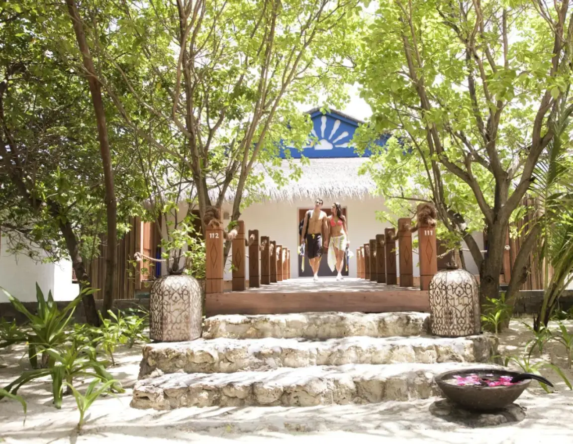 Camino que conduce a una suite en Taj Coral Reef Resort & Spa con vegetación exuberante