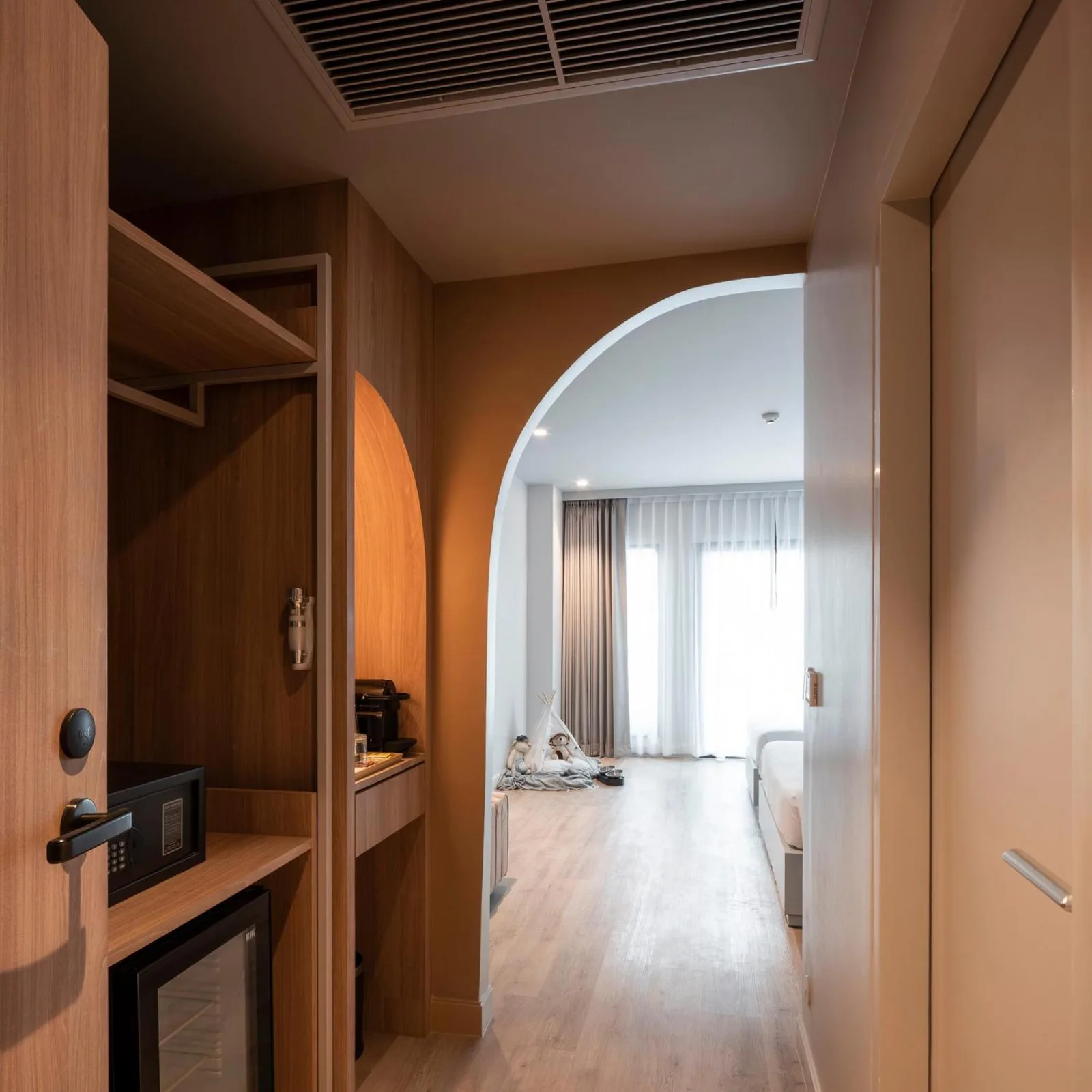 Flur im Hotelzimmer Terra Nara Pattaya mit Holzschränken, gewölbtem Durchgang und modernem Innendesign.