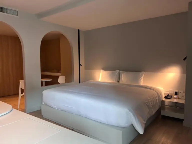 Suite mit Kingsize-Bett im Hotel Terra Nara in Pattaya mit warmem Licht, gewölbtem Durchgang und Sitzbereich.
