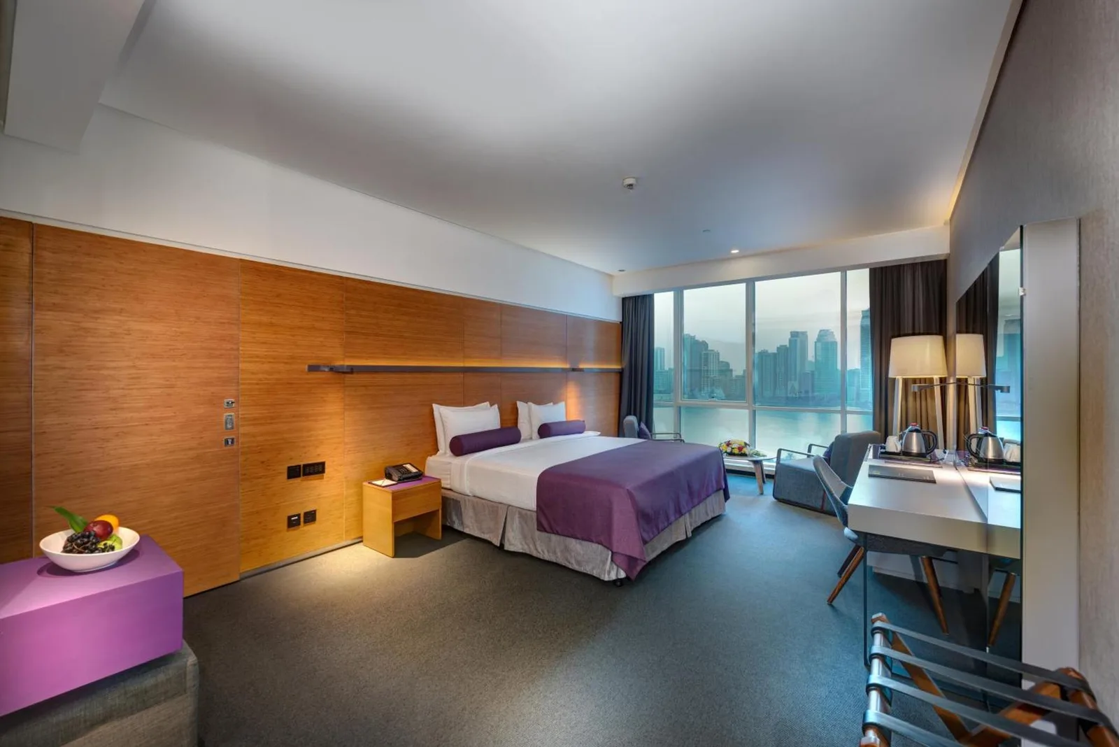 The Act Hotel Sharjah king room with bed, work desk, and panoramic waterfront view.