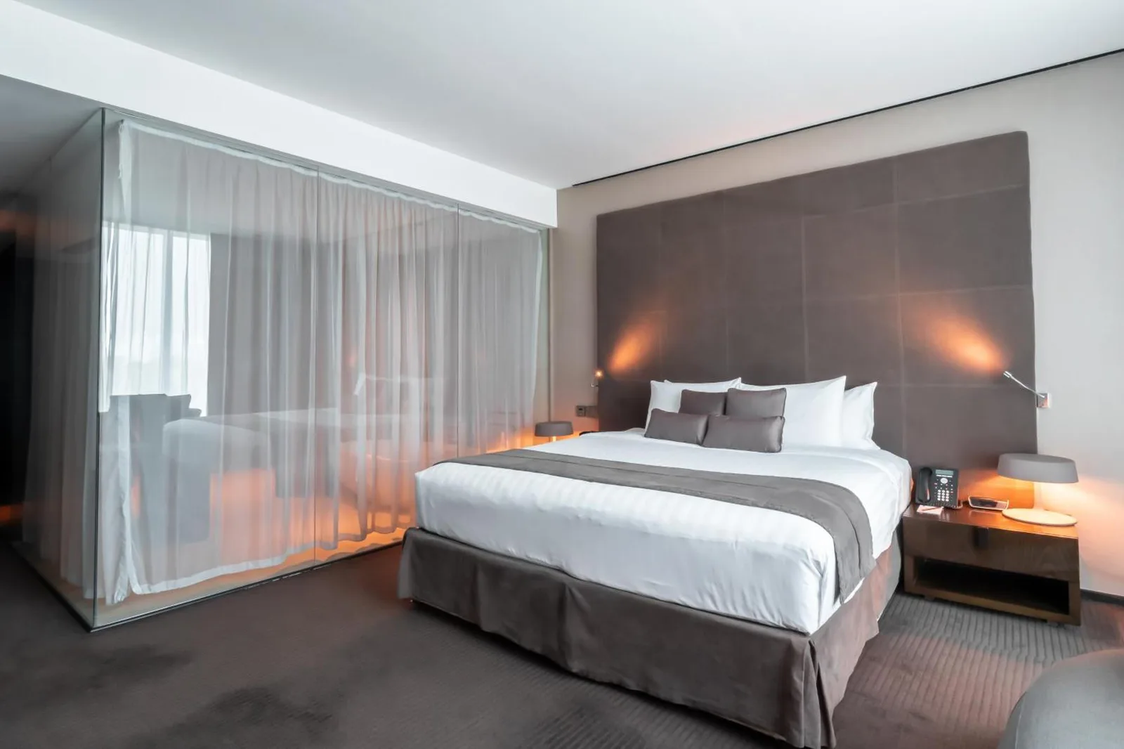 Bedroom at The Canvas Dubai - MGallery Hotel Collection in Dubai with a king bed, soft lighting, and sheer curtains.