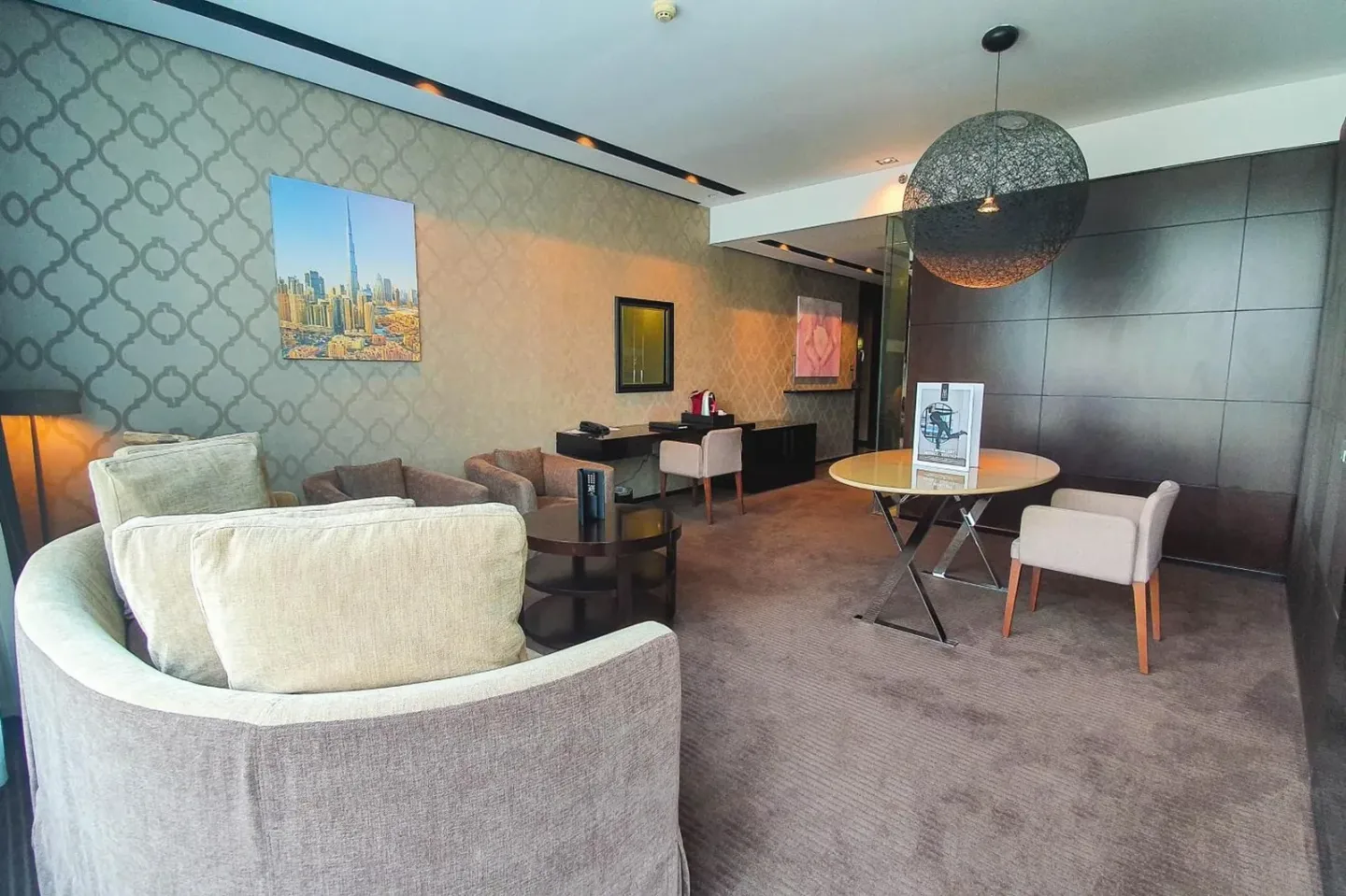 Living area in a suite at The Canvas Dubai - MGallery Hotel Collection in Dubai with sofa seating and dining table.