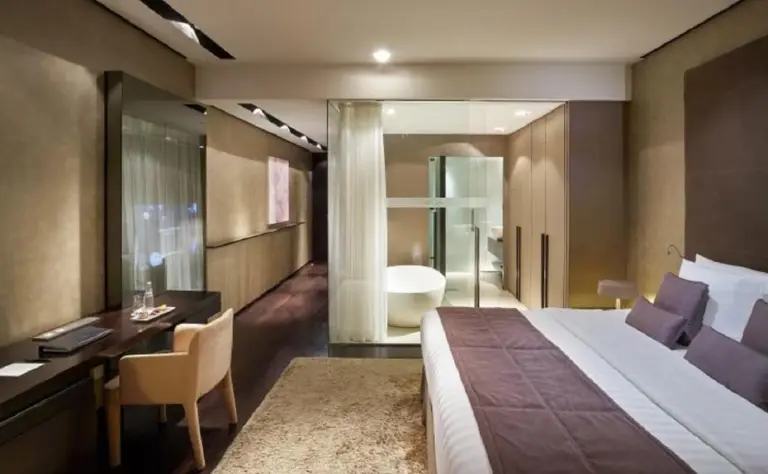 Spacious room suite at The Canvas Dubai - MGallery Hotel Collection in Dubai with desk, bed, and bathroom area.