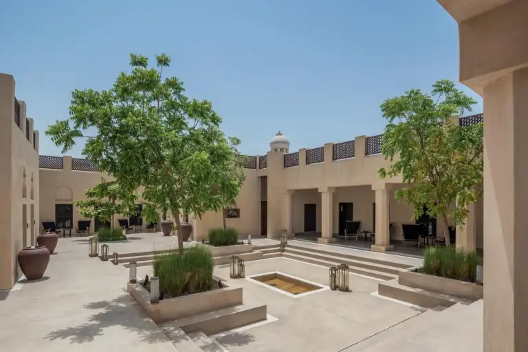 The Chedi Al Bait courtyard with lush trees and seating