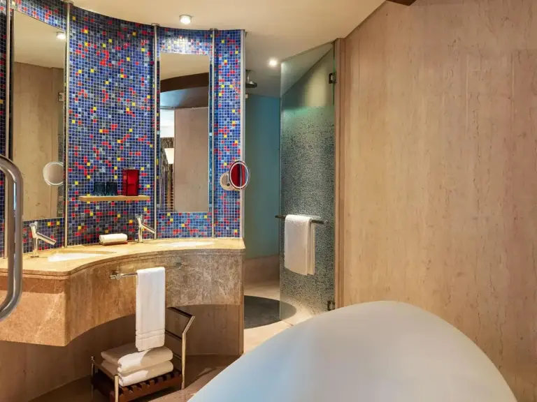 Luxury bathroom at The Creekside Hotel, Dubai, an Accor Hotel, featuring a freestanding bathtub and mosaic tile details
