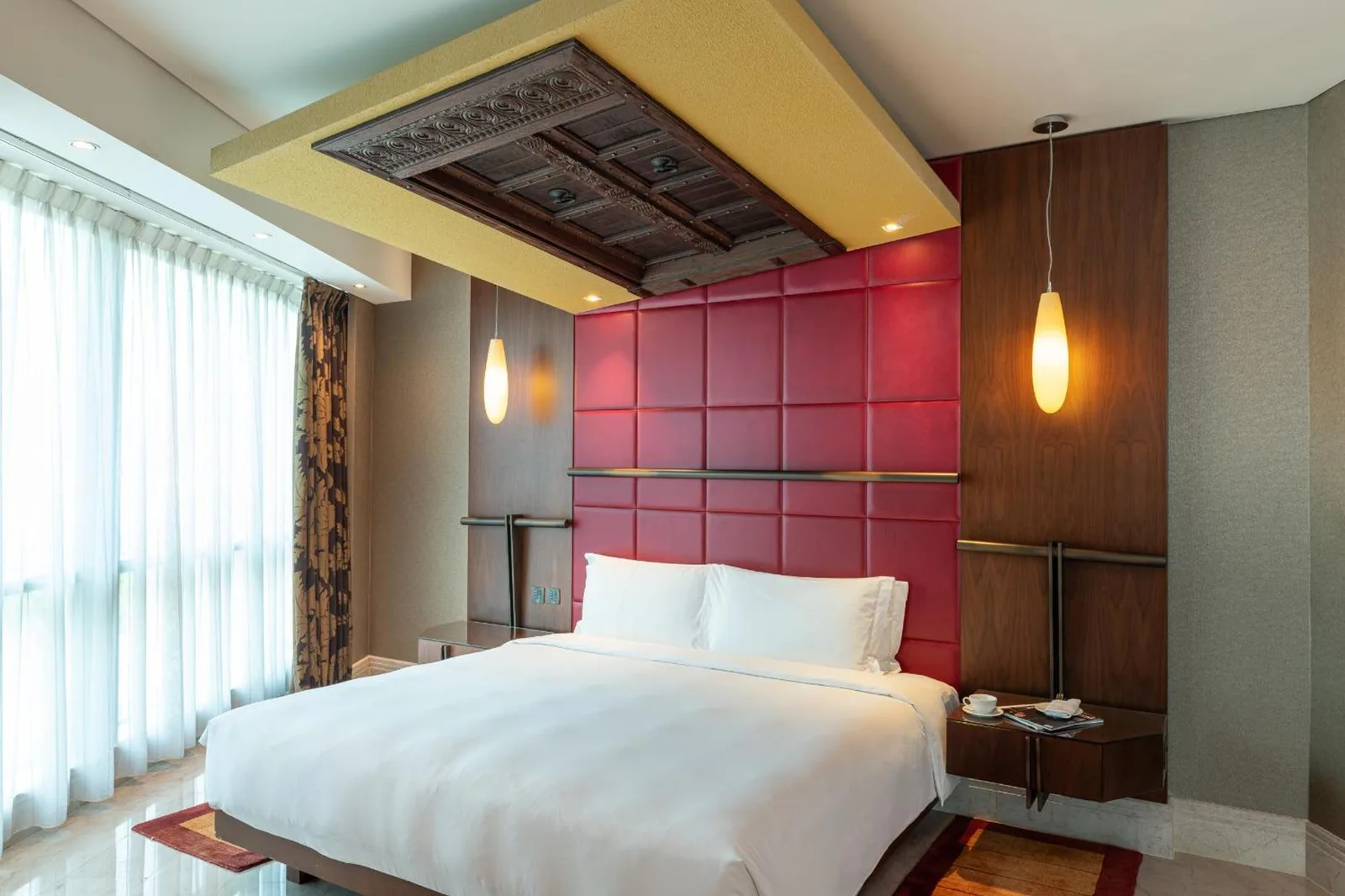 King bedroom at The Creekside Hotel, Dubai, an Accor Hotel, with red headboard, white linens, and natural light