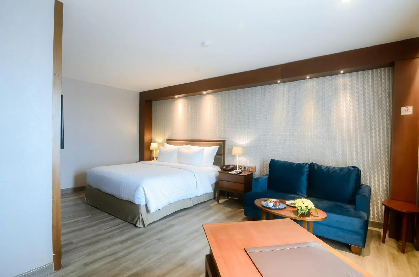 Studio room at The Excelton Hotel Palembang with a bed, sofa, desk, and bathroom access
